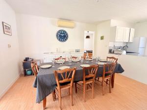 a dining room table with chairs and a clock on the wall at La maison des suisses in Saint-Denis-dʼOléron