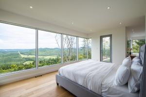 Un dormitorio con una cama grande y grandes ventanales. en Villa Summit Movie Theater Game room Views Hot Tub & Sauna, en La Conception