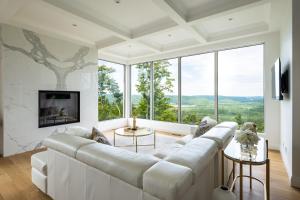 Una sala de estar con un sofá blanco y grandes ventanales. en Villa Summit Movie Theater Game room Views Hot Tub & Sauna, en La Conception