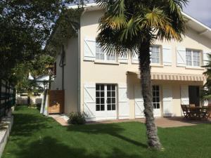 a palm tree in front of a white house at Totem Sud in Arcachon