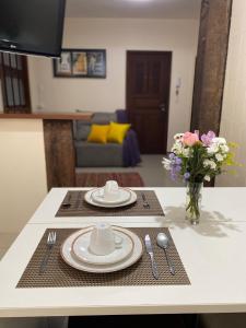 a table with two plates and a vase of flowers at Apartamento no Centro Histórico in São João del Rei