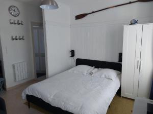 a bedroom with a white bed and a clock on the wall at Les Vagues - Séjour Plage et Falaises au centre d'Etretat in Étretat