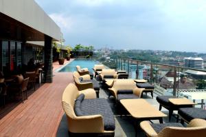un balcone con tavoli, sedie e piscina di Louis Kienne Hotel Simpang Lima a Semarang
