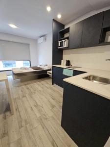 a kitchen with black cabinets and a wooden floor at Alquiler Temporario Rosario 23 in Rosario