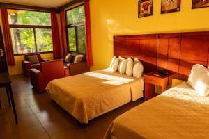 a hotel room with two beds and a chair at Grand Caporal Hotel in Chiquimula