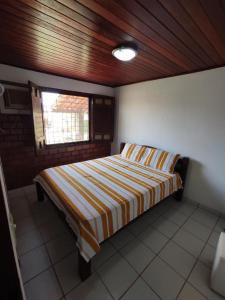 Un dormitorio con una cama con edredón de rayas y una ventana. en Casa em Gravata, en Gravatá