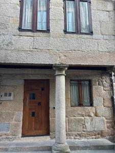 a building with a wooden door and a pillar at GaliciaGuestHome Figueroa 27 in Pontevedra