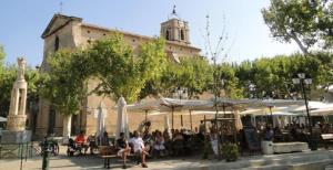 a group of people sitting at tables in front of a building at La maussanaise in Maussane-les-Alpilles