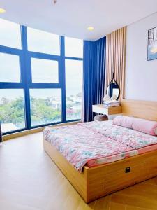 a bedroom with a large bed and large windows at Khu Nghỉ Dưỡng Aria Resort Vũng Tàu - DN Apartment in Vung Tau