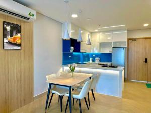 a kitchen with a table and chairs and a kitchen with blue at Khu Nghỉ Dưỡng Aria Resort Vũng Tàu - DN Apartment in Vung Tau
