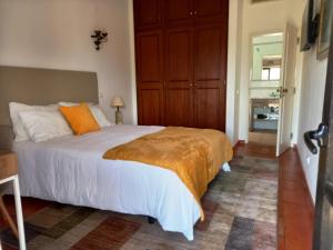 a bedroom with a large bed with an orange blanket at Quinta das AVES - Double Bedroom 1 in Odiáxere