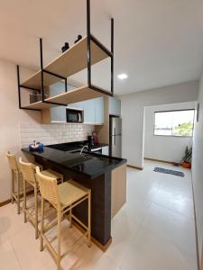 a kitchen with a black counter top and chairs at Casa da Alê in Camaçari