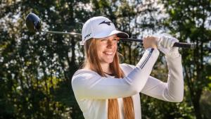 a woman with long red hair swinging a golf club at Sonnenhof Resort Himmelreich Bayerischer Wald in Lam
