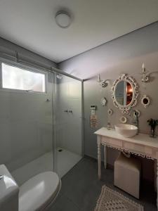 une salle de bains avec douche, lavabo et miroir dans l'établissement Refugio Familiar em Monte Verde, à Monte Verde