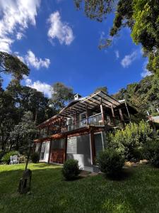 une maison entourée d'une terrasse couverte sur une pelouse dans l'établissement Refugio Familiar em Monte Verde, à Monte Verde 44 autres photos