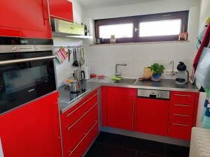 a small kitchen with red cabinets and a sink at Ferienhaus Berge und See mit Whirlpool und Sauna in Rimsting