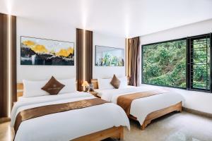 two beds in a room with two windows at Cat Ba Rose Nhung Hotel in Cat Ba