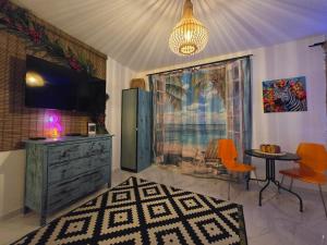 Una sala de estar con un televisor y una mesa y sillas. en GDAŃSK by the Sea - PRESTIGE HOME SPA Apartments with a luxurious JACUZZI, SAUNA and an exclusive Massage Chair available in one of the apartments!, en Gdansk