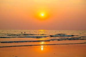 a sunset on the beach with two people in the water at Kacha Resort & Spa, Koh Chang in Ko Chang