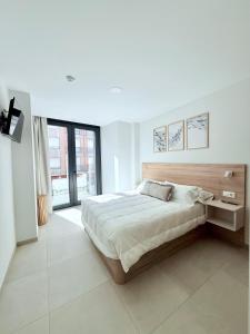 a white bedroom with a large bed and a window at Apartamentos Limar Portonovo - Sanxenxo in Portonovo