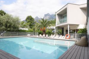 a swimming pool with chairs and a house at Camping Al Porto - Mini Glamping & Mobile Homes in Nago-Torbole