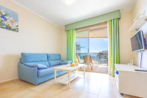Sala de estar con sofá azul y vistas al océano en Apartment of Joy Piscina Aparcamiento, en Calpe