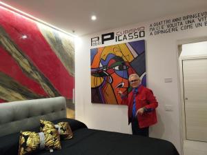 a man standing in a room with a painting at La Dimora dell'Artista in Mazara del Vallo
