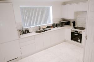 a white kitchen with white cabinets and a window at Apsley Way, 5 bed 4 bathroom house in Thornaby on Tees