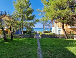 a walkway through a park with trees and the ocean at Porto Blue Horizon in Pefkohori