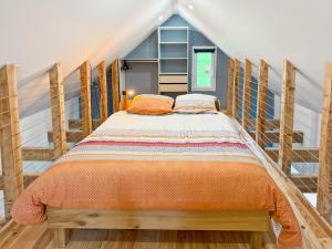 a bedroom with a bed with an orange comforter at Maison au cœur de la vallée du Cantal - 2pers in Lascelle