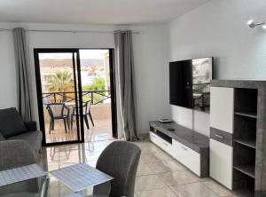 a living room with a couch and a television and a balcony at Casa Serena in Los Cristianos