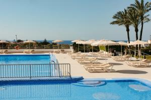 a swimming pool with lounge chairs and umbrellas at Minura Sur Menorca in Punta Prima
