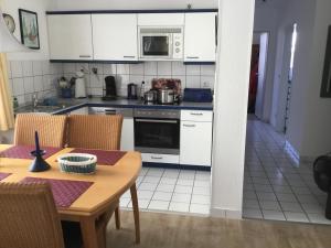 a kitchen with white cabinets and a wooden table with a dining room at Zinnowitz, Dünenstr 36 WE 3 in Zinnowitz
