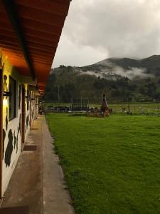 a building with a green field and mountains in the background at Finca Castillo de Altura in San Juan