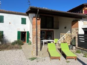 a patio with green chairs and a table and a building at Casa delle Fate - between Nature and Harmony in Boccon