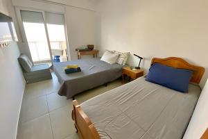a small bedroom with two beds and a chair at Brisa à Beira-Mar: Desfrute do melhor no Gonzaga in Santos