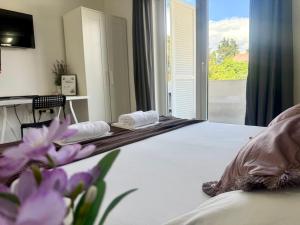 a bedroom with a bed with a window and purple flowers at Apartments Ana & Ita in Novalja