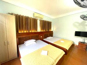 a small room with two beds and a television at Tuân Thuỷ hotel đảo Quan Lạn in Làng Liễu