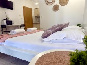 a large bed with white sheets and pillows on it at Apartments Ana & Ita in Novalja
