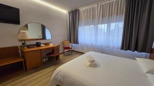 a hotel room with a bed and a desk and a mirror at Hotel Cristallo in Udine +134 photos
