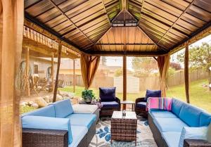 a patio with blue couches and chairs under a roof at 2 Bedroom Private 1500ft Hot Tub Sauna Gym in Graham