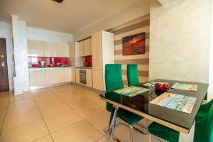 a kitchen with a dining table and green chairs at Mamaia Lake View Apartament in Mamaia