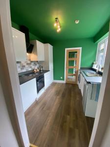 een lege keuken met groene muren en houten vloeren bij Salty Escape in Saltburn-by-the-Sea +13 foto's