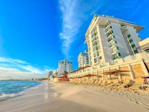 a beach with lounge chairs and buildings on it at Paradisiaca Suite Cancun - BEACH CONDO - 4PX in Cancún