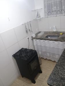 a small kitchen with a stove and a sink at Verde Mar Abricó 3 in Rio das Ostras