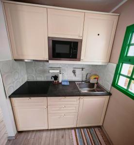 a kitchen with white cabinets and a sink and a microwave at La casa di marcos in Costa Calma
