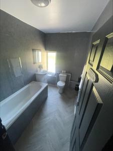 a bathroom with a bath tub and a toilet at 1 Bed Flat with King or Twin Beds, Sofa Bed, Work space, Dining and SMART TV with Free Wifi Throughout! in Wingate +23 photos