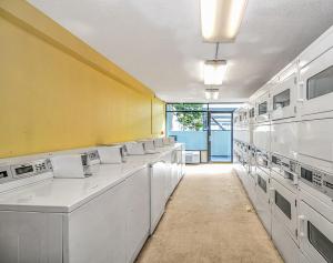 a laundry room with white washing machines and a yellow wall at Modern & Updated Oceanview Studio! Sleeps 4! Landmark 523 in Myrtle Beach
