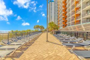 a row of chaise lounge chairs on a walkway next to a building at Modern & Updated Oceanview Studio! Sleeps 4! Landmark 523 in Myrtle Beach