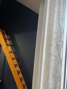 a curtain in a window next to a ladder at La Maison Téranga au Bourg de Villenave in Courrejean